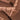 Close-up of a broken milk chocolate bar, showing rough and smooth textures with jagged edges and layered surfaces in various shades of brown.