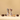 Two wrapped nougatine candies stand upright between three whole chocolate-coated candies and one cut open to show a nutty center, all on a neutral beige background.