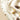 Assorted chocolate eggs, candies, and small wrapped chocolates are arranged on a cream-colored cloth with fringed edges under soft, warm lighting.