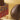 A chocolate egg sits on a colorful floral-patterned box next to another boxed egg; pieces of chocolate and scattered crunchy bits are nearby.