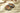 A round, decorative box filled with assorted chocolates sits open on a cream-colored fabric with two people nearby, one holding a wine glass. - AI generated text